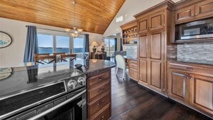 Eine Küche mit Holzausstattung, einer schwarzen Arbeitsplatte und einem großen Fenster mit Blick auf eine schöne Landschaft.