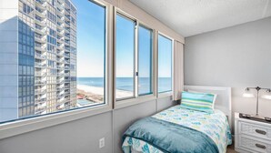A bedroom with a large window overlooking a beach and a high-rise building. - Quay-3 Bedroom Ocean Front Condo (Ocean City)