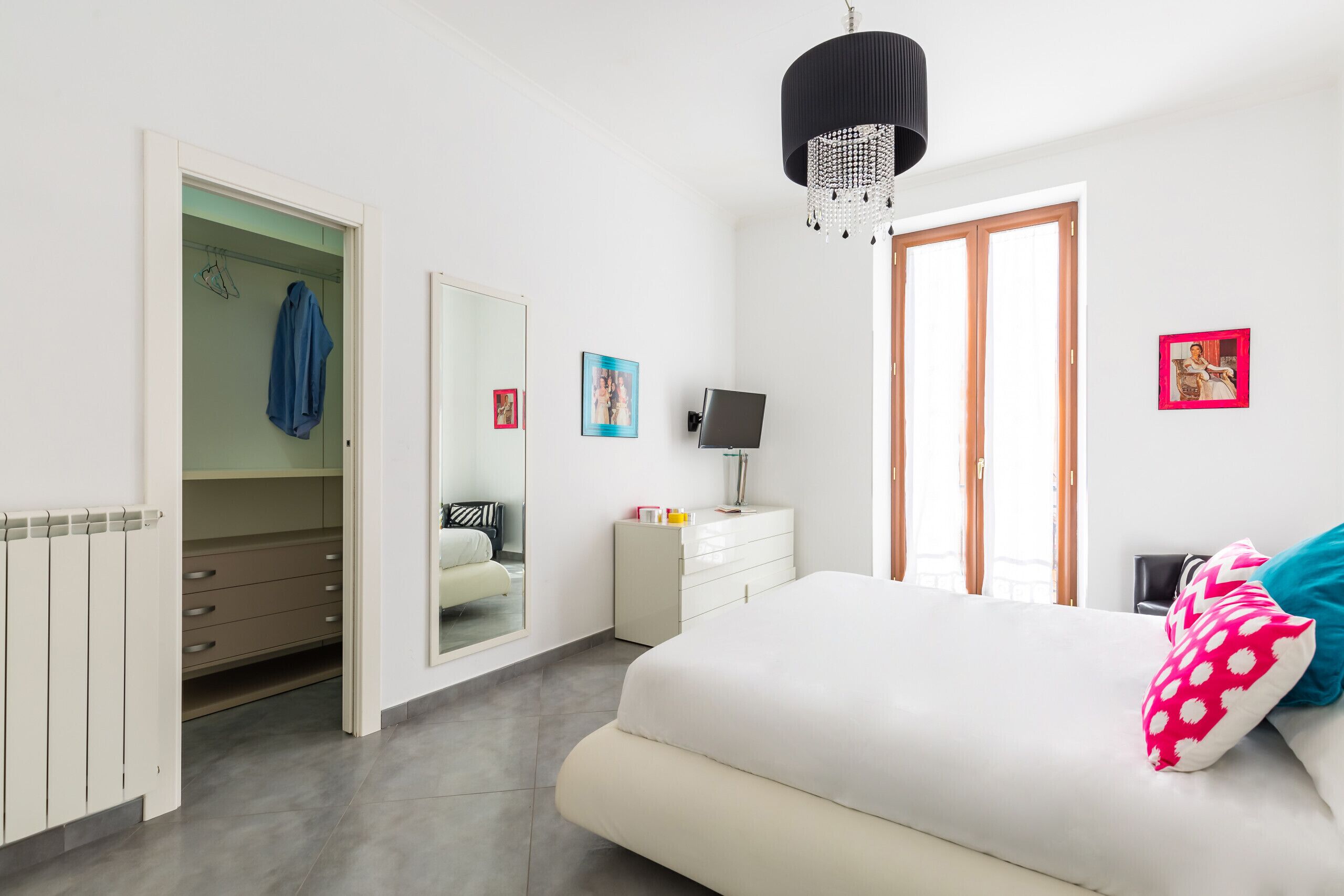 Un dormitorio con cama, armario, espejo, cómoda y lámpara de araña.