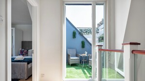 A modern apartment with a balcony, a bed, a small table, and a chair.