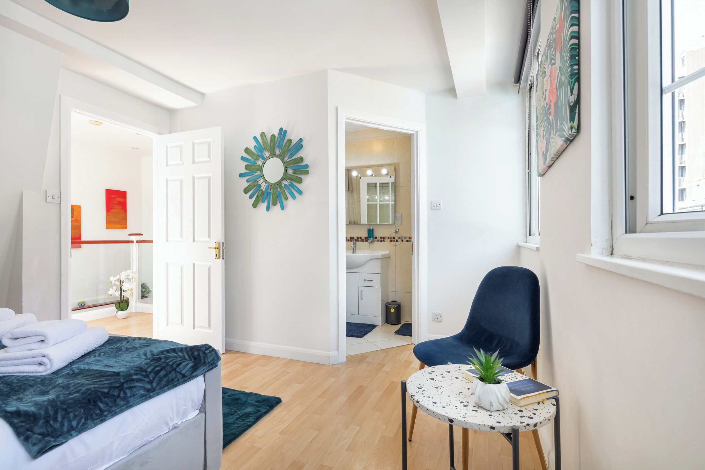 A modern bedroom with a bed, a small round table with a plant, and a chair.