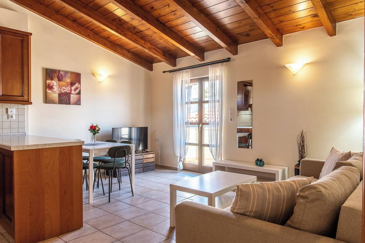 A modern living room with a wooden ceiling, a dining area, and a kitchen.