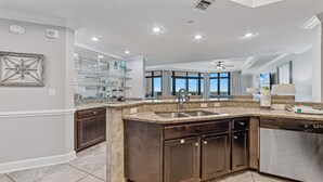 A modern kitchen with granite countertops, dark cabinetry, and a large island with a sink. - Oasis, formerly Phoenix West II 4BR!!  New Adult Pool,  Lazy River/Slide!! (Orange Beach)