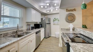 A modern kitchen with granite countertops, stainless steel appliances, and a backsplash. - 224 El Matador 1 Bedroom Condo by RedAwning (Fort Walton Beach)