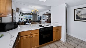 A modern kitchen with a central island, wooden cabinets, and a black stove.