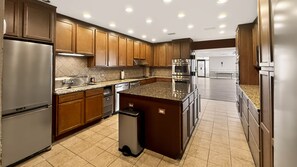 A modern kitchen with stainless steel appliances, wooden cabinets, and a granite countertop. - 110 El Matador 2 Bedroom Condo by RedAwning (Fort Walton Beach)