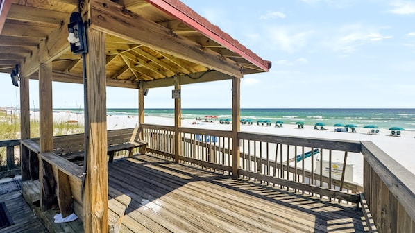 A wooden deck with a view of the beach and ocean.