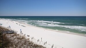 A beach with a sandy shore, a wooden fence, and a clear blue sky.