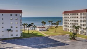 Un hotel con piscina, palmeras y vista al océano.