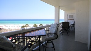 Un balcón con vistas a la playa, una mesa y dos sillas.