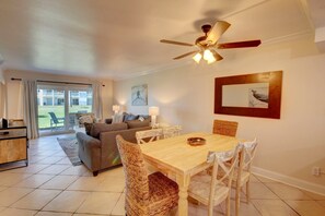 A living room with a sofa, dining table, chairs, and a ceiling fan.