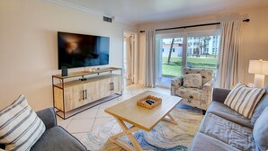 Un salon moderne avec un téléviseur à écran plat, un meuble en bois, un canapé et un fauteuil.