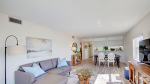 A modern living room with a sofa, coffee table, and dining area. - 530 El Matador 2 Bedroom Condo by RedAwning (Fort Walton Beach)