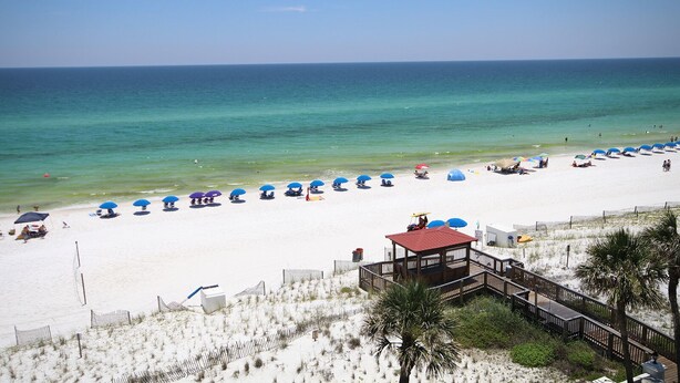 A beach with white sand, clear blue water, and a wooden structure with a red roof. - 362 El Matador 2 Bedroom Condo by RedAwning (Fort Walton Beach)