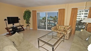 A living room with a sofa, a glass coffee table, a television, and a plant. - 335 El Matador 1 Bedroom Condo by RedAwning (Fort Walton Beach)