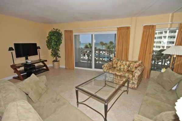 A living room with a sofa, a glass coffee table, a television, and a plant.