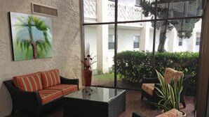 A modern living room with a glass coffee table, a sofa, and two armchairs. - 335 El Matador 1 Bedroom Condo by RedAwning (Fort Walton Beach)