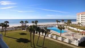 A resort with a pool, palm trees, and a view of the beach.