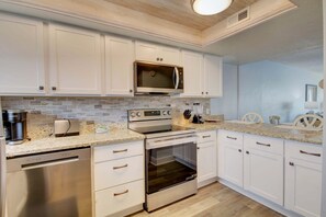 A modern kitchen with white cabinets, a built-in microwave, a stainless steel dishwasher, and an oven. - 358 El Matador 2 Bedroom Condo by RedAwning (Fort Walton Beach)