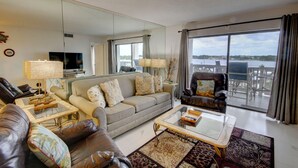 A spacious living room with a sofa, armchairs, a coffee table, and a large mirror.