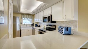 A kitchen with white cabinets, a microwave, a toaster, and a dishwasher. - 268 El Matador 2 Bedroom Condo by RedAwning (Fort Walton Beach)