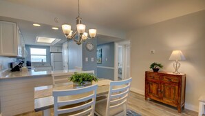 A modern kitchen with white cabinetry, a central island, and a chandelier. - 427 El Matador 2 Bedroom Condo by RedAwning (Fort Walton Beach)