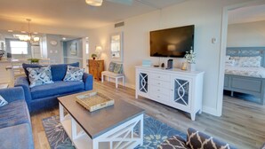 A modern living room with a blue sofa, white cabinet, and a flat-screen TV. - 427 El Matador 2 Bedroom Condo by RedAwning (Fort Walton Beach)