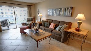 A living room with a sofa, armchairs, a coffee table, and two lamps. There is a sliding glass door leading to an outdoor area. - 337 El Matador 2 Bedroom Condo by RedAwning (Fort Walton Beach)