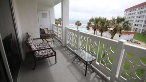 A balcony with a seating area, white railing, and a view of the ocean and hotel buildings. - 337 El Matador 2 Bedroom Condo by RedAwning (Fort Walton Beach)