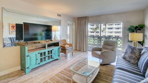 A living room with a television, a sofa, a coffee table, and a wicker chair.