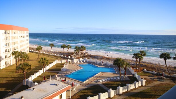 A hotel with a pool, beach, and ocean view.