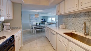A modern kitchen with white cabinetry, a large island, and a tiled backsplash. - 554 El Matador 1 Bedroom Condo by RedAwning (Fort Walton Beach)