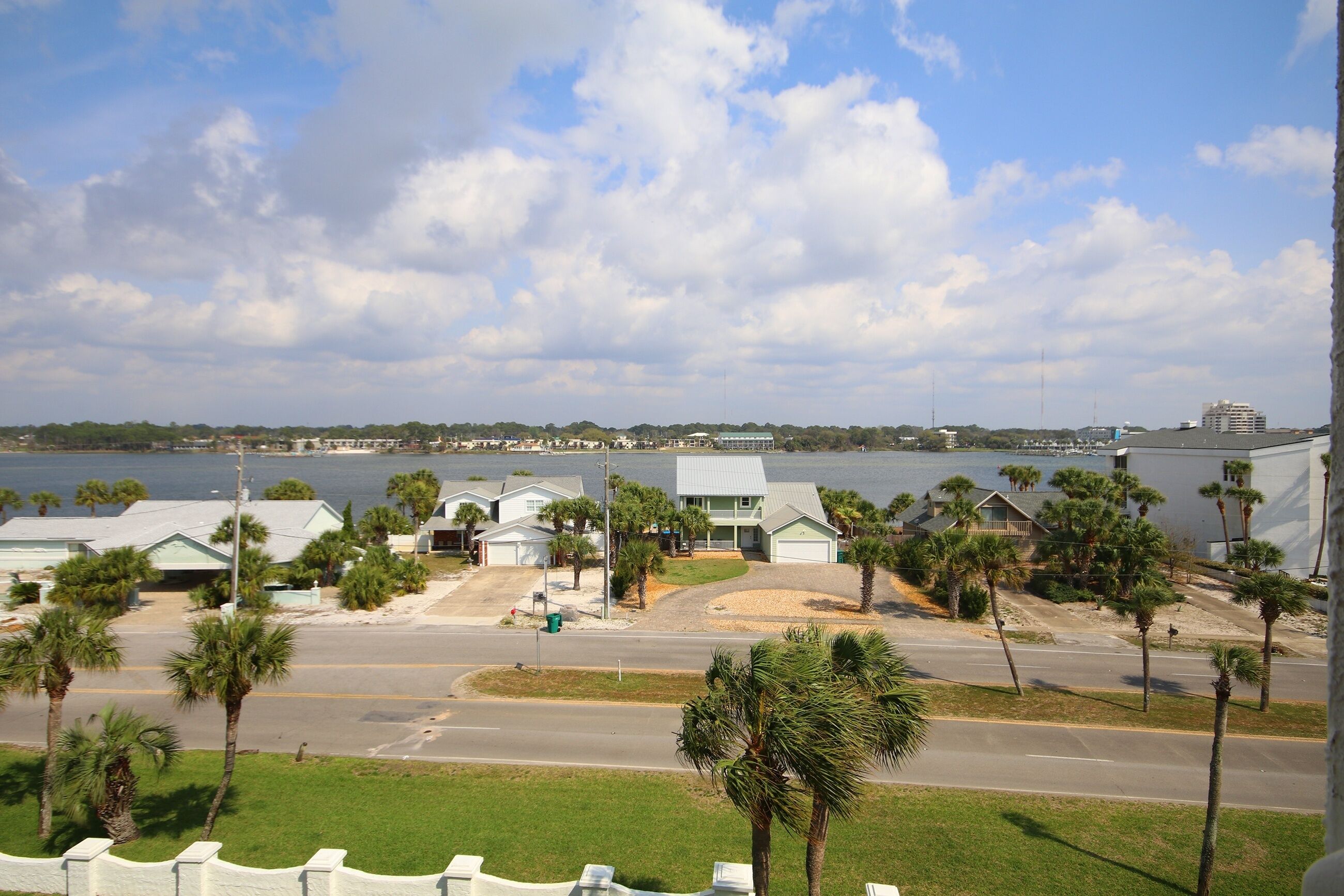 A coastal residential area with houses, palm trees, and a view of the water.