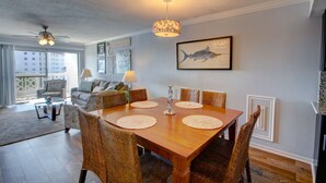 A dining area with a wooden table, wicker chairs, and a chandelier.