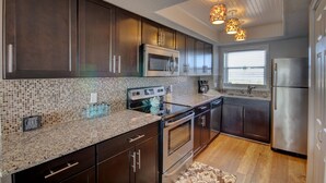 A modern kitchen with dark wood cabinets, stainless steel appliances, and a mosaic tile backsplash.