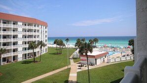 A hotel with multiple balconies overlooking a beach and pool area.
