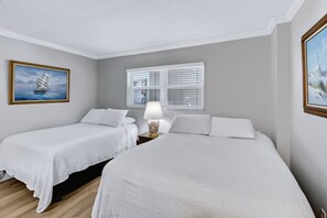 A hotel room with two beds, a window with blinds, a lamp, and two paintings on the walls. - 440 El Matador 2 Bedroom Condo by RedAwning (Fort Walton Beach)