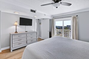 A hotel room with a bed, a TV, a dresser, and a balcony with a city view. - 440 El Matador 2 Bedroom Condo by RedAwning (Fort Walton Beach)