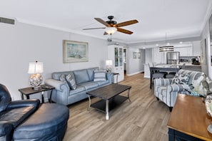 A modern living room with a sofa, armchair, coffee table, and a dining area with a table and chairs.