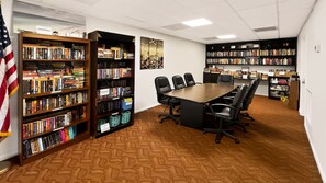 Ein Konferenzraum mit einem langen Tisch und Stühlen, umgeben von Bücherregalen voller Bücher.