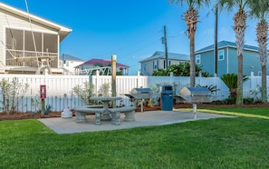 Enjoy a patio area with a barbecue grill and stone table, surrounded by a well-maintained lawn and white picket fence.