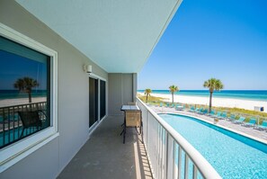 A balcony with a view of a beach and a pool. - Tradewinds 105 2 Bedroom Condo (Orange Beach)