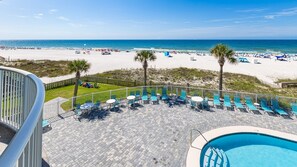 A pool area with lounge chairs and a view of the beach. - Tradewinds 203 1 Bedroom Condo (Orange Beach)