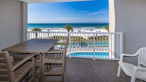 A balcony with a view of the beach and pool.