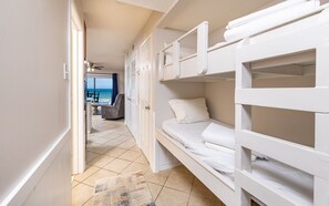 Een kamer met stapelbedden, een deur naar een balkon en uitzicht op zee.