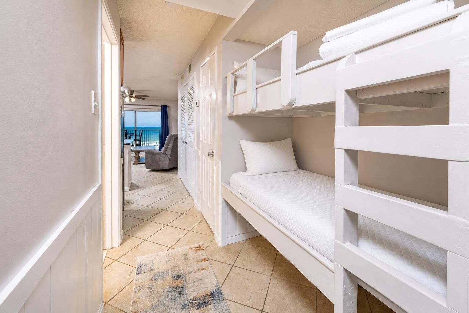 A compact room with bunk beds, a door leading to a balcony, and a view of the sea.