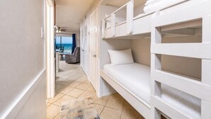 A compact room with bunk beds, a door leading to a balcony, and a view of the sea. - Tradewinds 203 1 Bedroom Condo (Orange Beach)