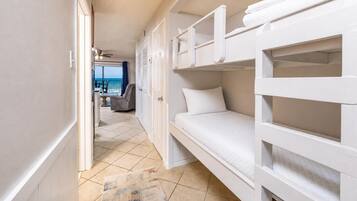 A compact room with bunk beds, a door leading to a balcony, and a view of the sea.