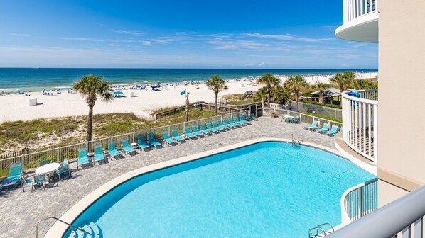 A pool area with a view of the beach and ocean.