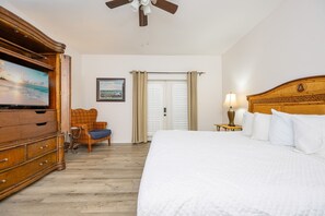 A hotel room with a bed, a television, a chair, a desk, and a ceiling fan.